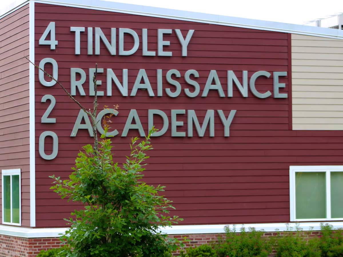 A red school building has large grey letters spelling "Tindley Renaissance Academy."