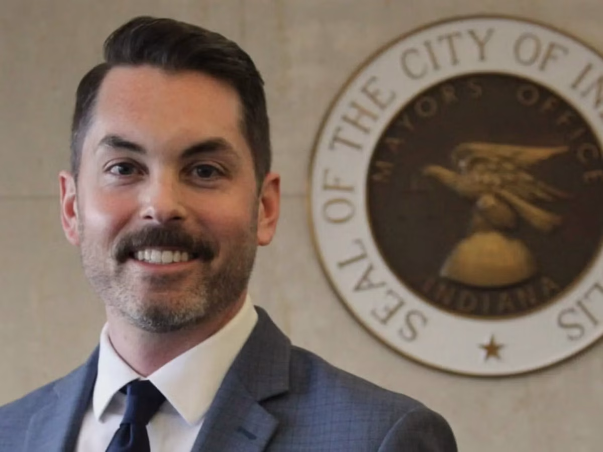 Andrew Merkley smiles for a photo in front of a seal of the city of Indianapolis.