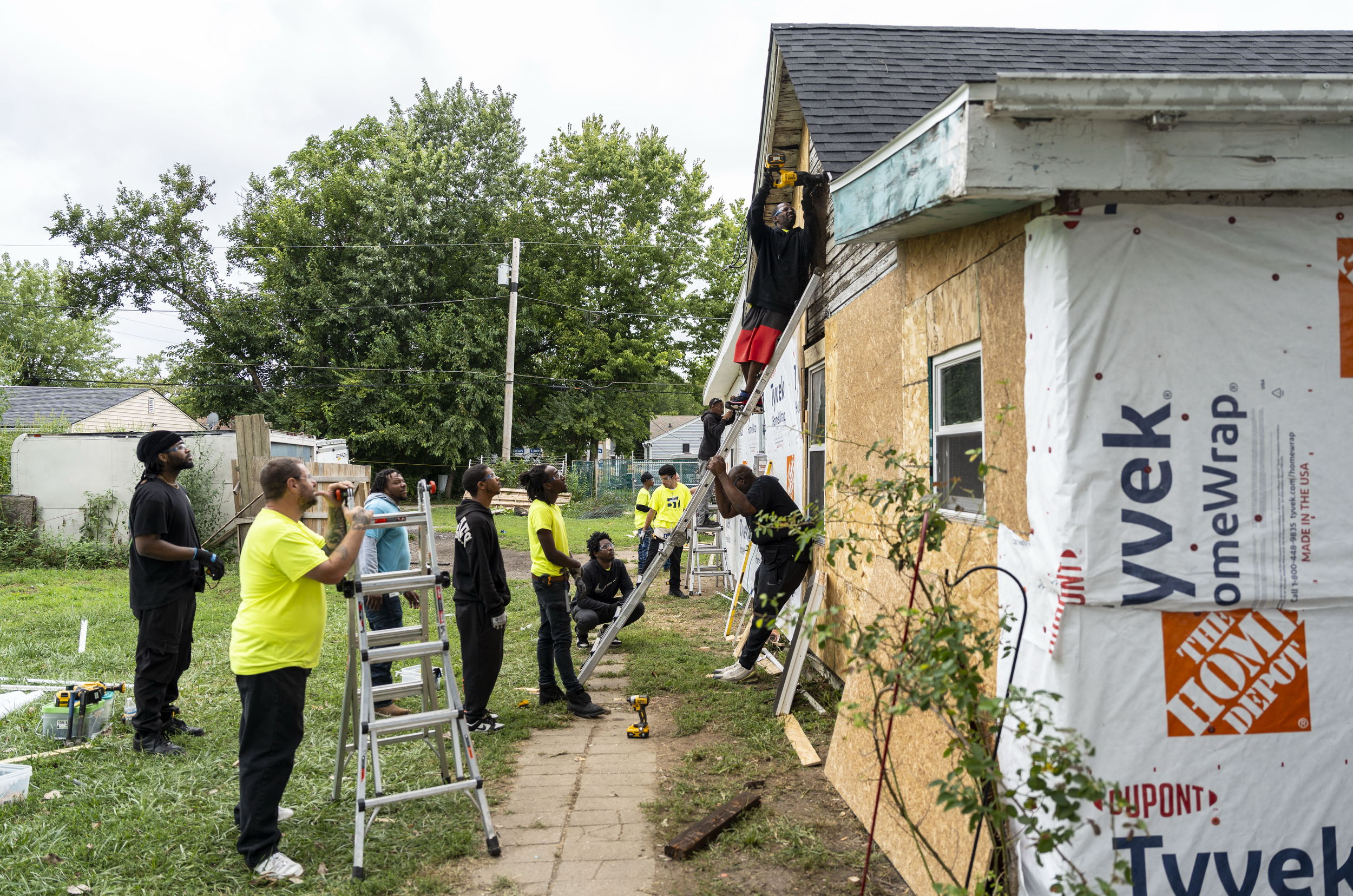 Tyrie Smith, (on the ladder) a student with the Indiana Construction Roundtable Foundation, cuts the frame for a window during a work experience program with Home Repairs for Good on Aug. 21, 2025, in Indianapolis.