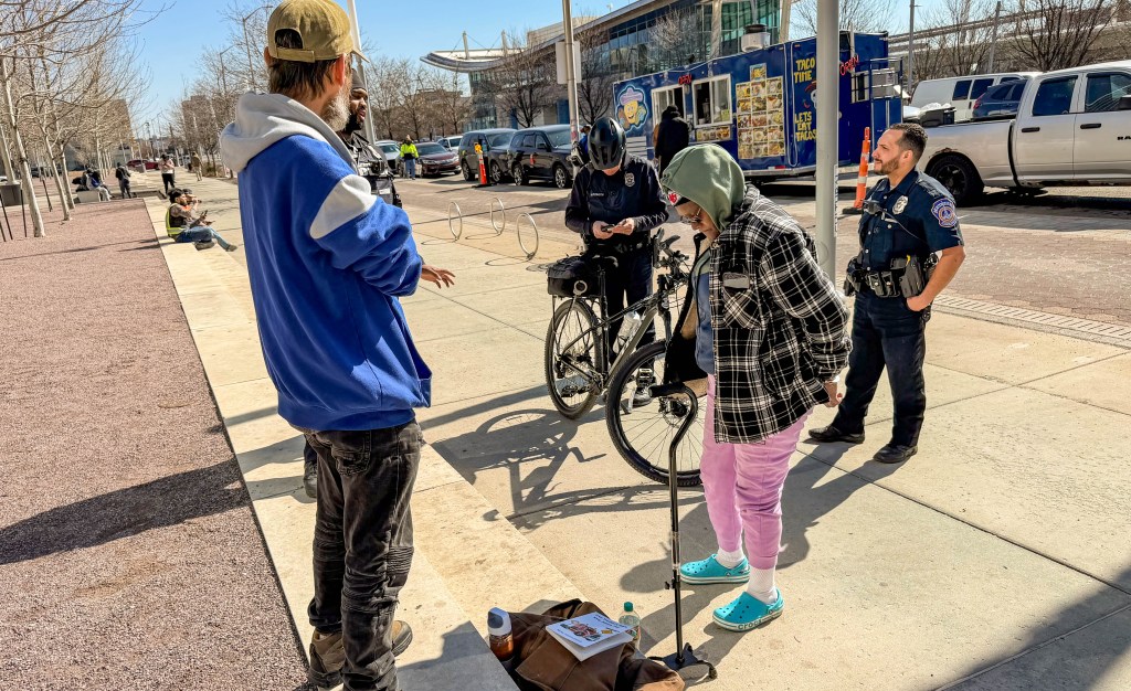 Indianapolis Metropolitan Police Department officers place a woman in handcuffs Feb. 27, 2026, at Lugar Plaza after discovering a warrant related to driving with a suspended license.